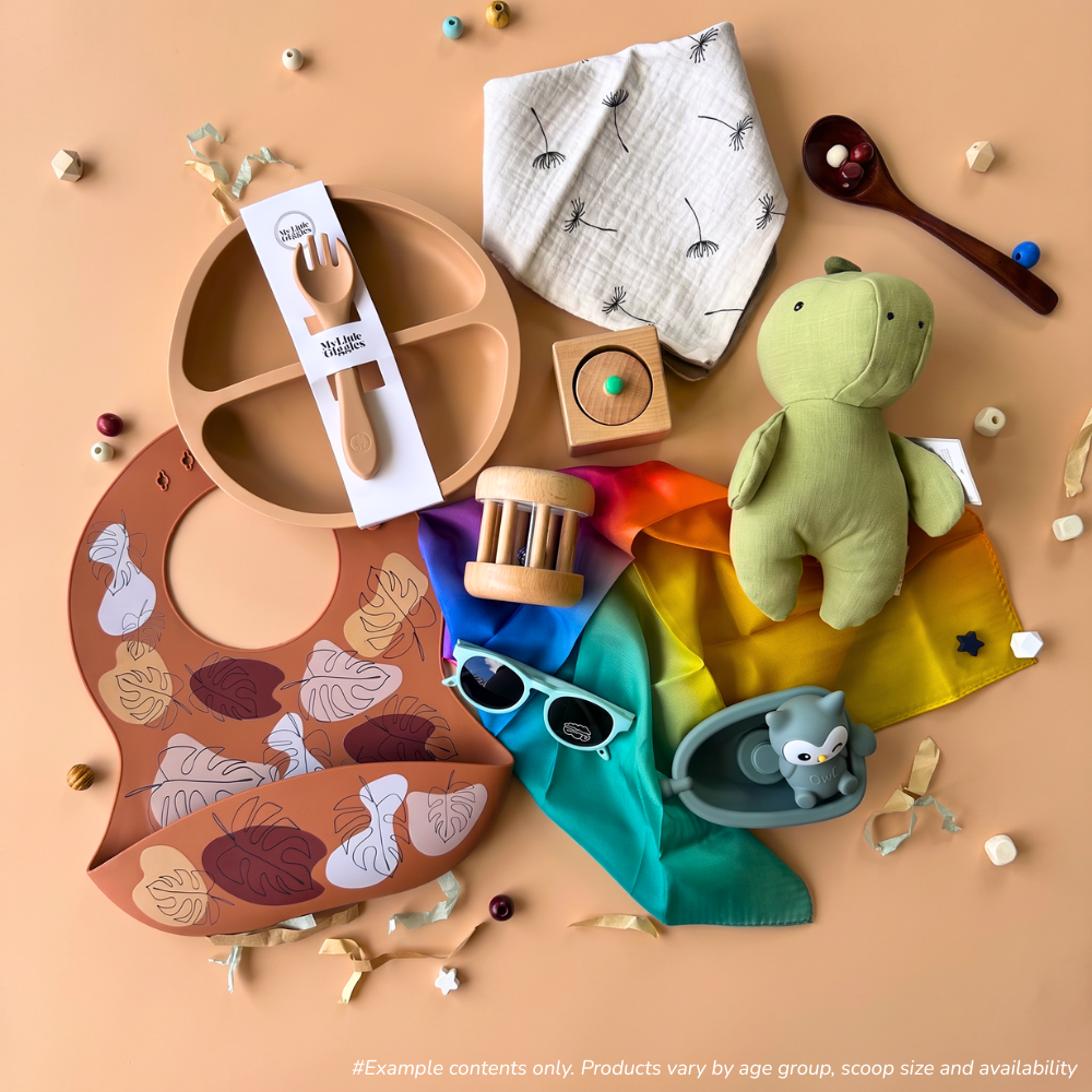 6-12 Month baby sensory gift box flat-lay of a 2-scoop order including a dribble bib from Spillykins, a silicone plate and fork set from My Little Giggles, a pincer puzzle from Totli, a rolling rattle from Totli, a silicone food bib from Spillykins, a mini rainbow play silk from Play Silkies, a linen animal toy from Living Textiles, and a bath toy from Toyslink,